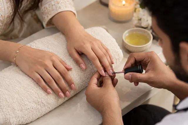 Beautician applying a nude-pink manicure